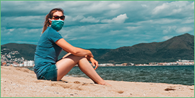 Germany Corporate Payment Survey 2021: Learning to live with the pandemic. The image is a photo of a womean wearing a face mask and sunglasses, sitting on a beach.